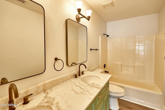 bathroom with visible vents, toilet, washtub / shower combination, vanity, and wood finished floors