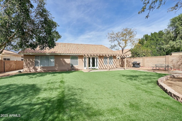 back of property with a patio, stucco siding, a lawn, a fenced backyard, and a tiled roof