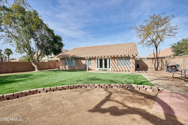 back of property with a patio, a lawn, a tile roof, and a fenced backyard