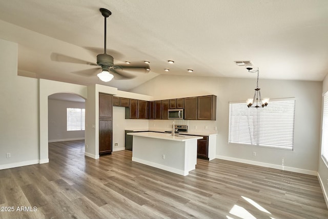 kitchen with lofted ceiling, appliances with stainless steel finishes, wood finished floors, light countertops, and pendant lighting