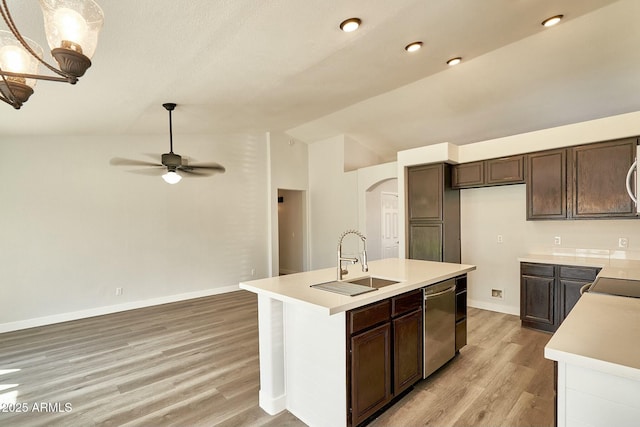 kitchen featuring lofted ceiling, a kitchen island with sink, stainless steel appliances, a sink, and light countertops