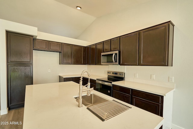 kitchen with stainless steel appliances, light countertops, and a kitchen island with sink