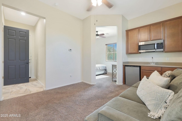 kitchen with sink, stainless steel appliances, light carpet, and ceiling fan