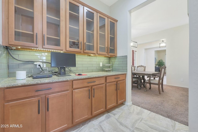 kitchen featuring tasteful backsplash, light colored carpet, and light stone countertops