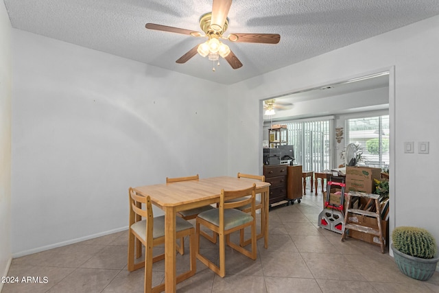 tiled dining room with a textured ceiling and ceiling fan