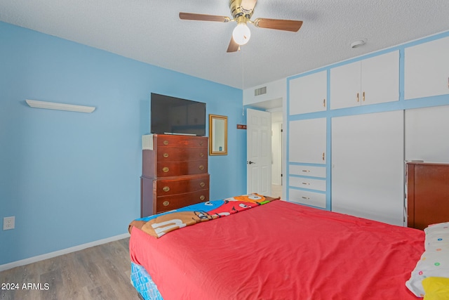 bedroom with a textured ceiling, light wood-type flooring, and ceiling fan