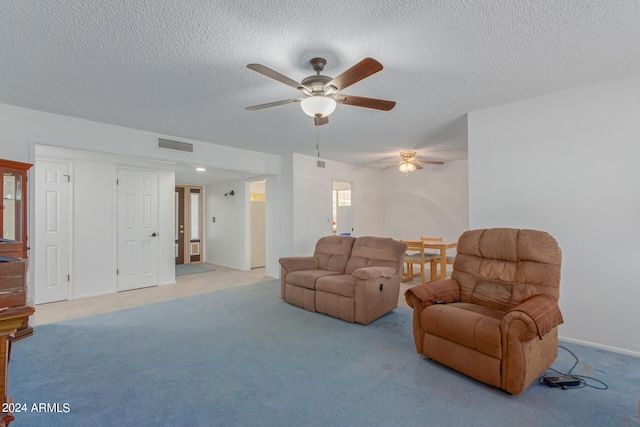 living room with a textured ceiling, light colored carpet, and ceiling fan