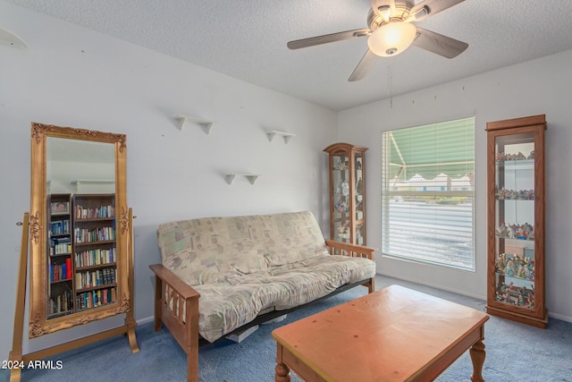 sitting room with ceiling fan, carpet flooring, and a textured ceiling