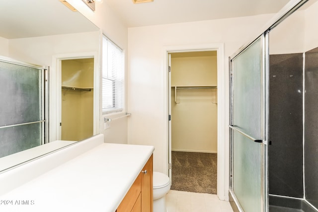 bathroom with tile patterned flooring, walk in shower, toilet, and vanity