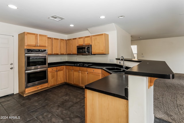 kitchen featuring dark tile patterned floors, kitchen peninsula, a kitchen bar, stainless steel appliances, and sink