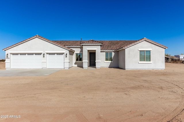 view of front of property with a tile roof, driveway, an attached garage, and stucco siding