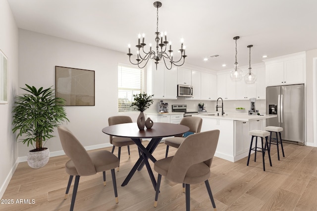 dining space featuring a notable chandelier, light wood finished floors, recessed lighting, visible vents, and baseboards