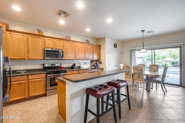 kitchen with sink, decorative light fixtures, a kitchen bar, a kitchen island with sink, and appliances with stainless steel finishes