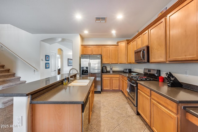 kitchen featuring sink, a breakfast bar area, light tile patterned floors, an island with sink, and stainless steel appliances