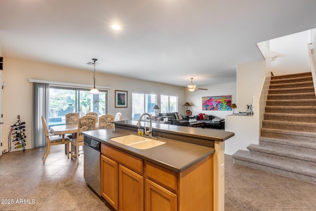 kitchen featuring ceiling fan, sink, stainless steel dishwasher, an island with sink, and decorative light fixtures