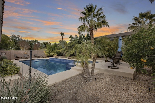 pool at dusk with a patio area