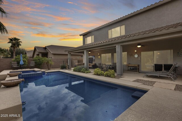 pool at dusk with a patio area, an in ground hot tub, ceiling fan, and an outdoor hangout area