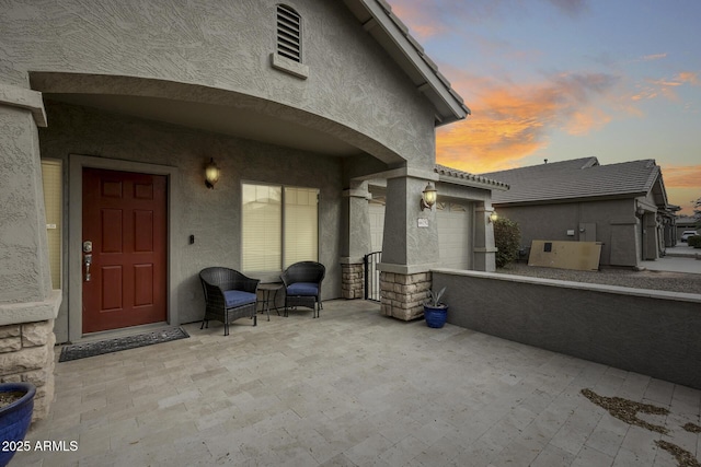 patio terrace at dusk featuring a garage