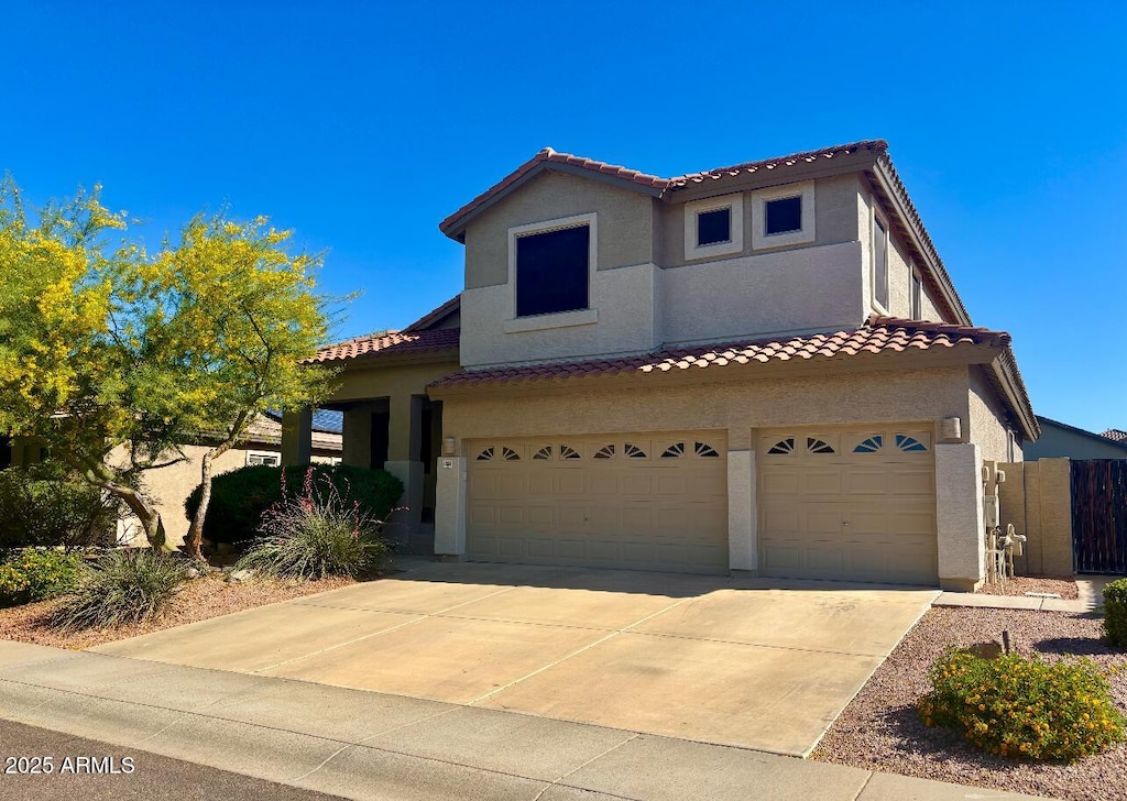 mediterranean / spanish house featuring a tiled roof, a garage, stucco siding, and concrete driveway