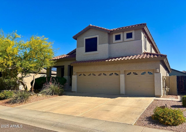 mediterranean / spanish house featuring a tiled roof, a garage, stucco siding, and concrete driveway
