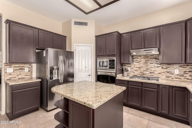 4834 E Robin Ln, Phoenix, AZ 85054 - kitchen featuring appliances with stainless steel finishes, under cabinet range hood, light tile patterned floors, tasteful backsplash, and light stone countertops