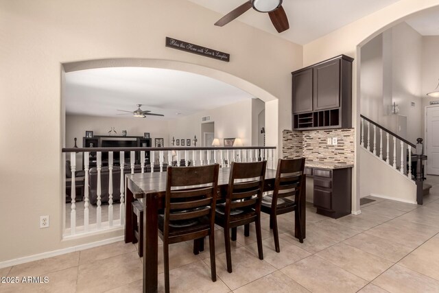 4834 E Robin Ln, Phoenix, AZ 85054 - dining space featuring ceiling fan, arched walkways, stairs, and light tile patterned flooring