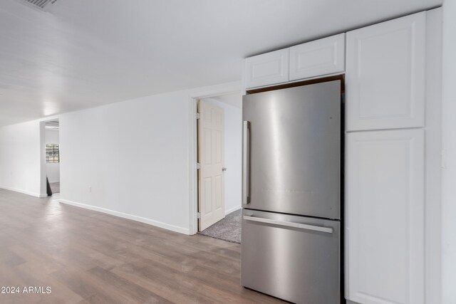 kitchen featuring hardwood / wood-style floors, white cabinetry, and stainless steel fridge