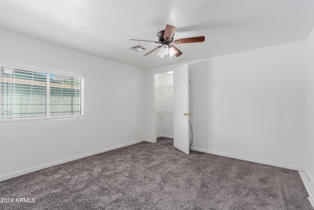 unfurnished bedroom featuring a spacious closet, a closet, carpet floors, and ceiling fan