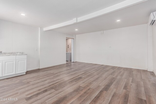 empty room with an AC wall unit and hardwood / wood-style floors