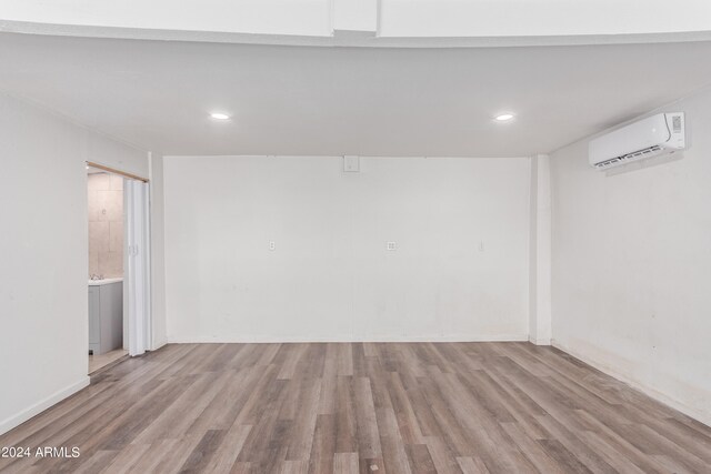 spare room featuring a wall unit AC and light hardwood / wood-style flooring