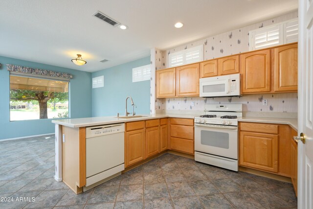 kitchen featuring sink, kitchen peninsula, white appliances, and decorative backsplash