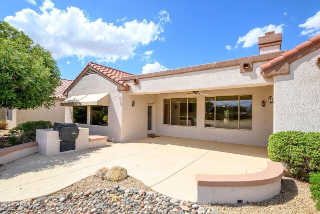 rear view of property featuring ceiling fan and a patio area