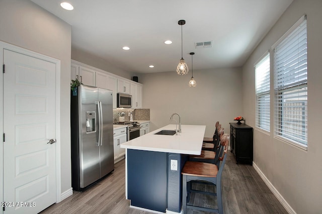 kitchen featuring stainless steel appliances, white cabinets, plenty of natural light, and decorative light fixtures