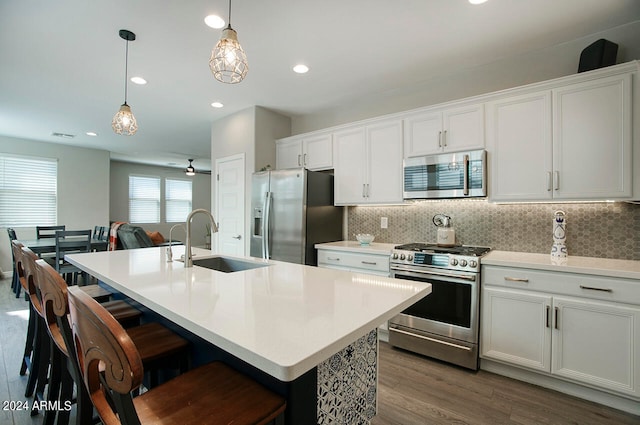 kitchen with hanging light fixtures, an island with sink, dark hardwood / wood-style flooring, stainless steel appliances, and sink