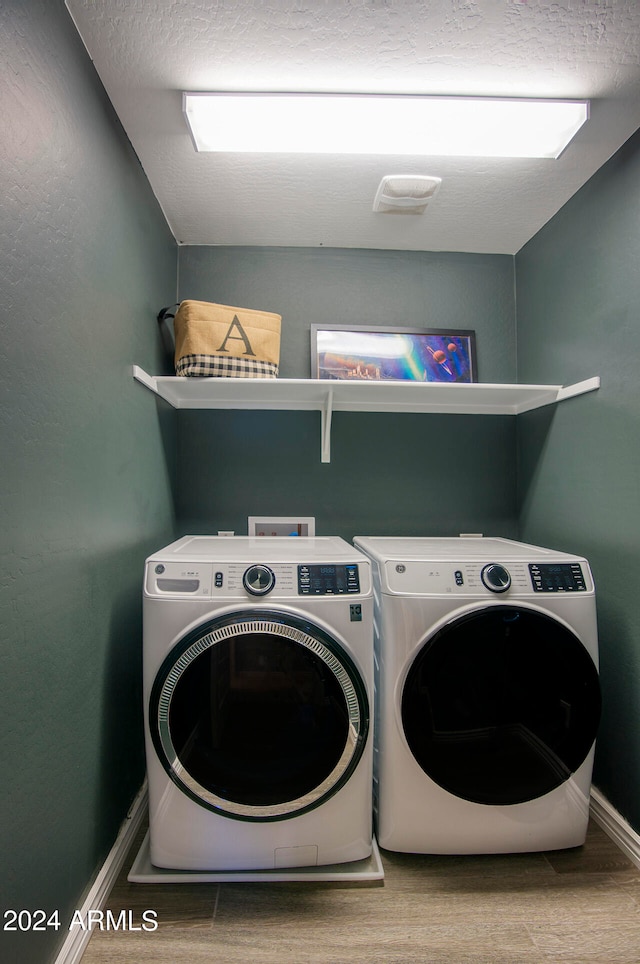 clothes washing area with wood-type flooring and separate washer and dryer