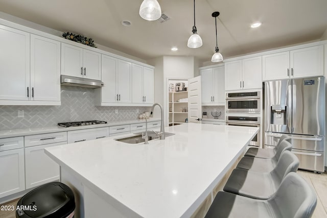 kitchen featuring decorative light fixtures, a breakfast bar area, appliances with stainless steel finishes, and tasteful backsplash