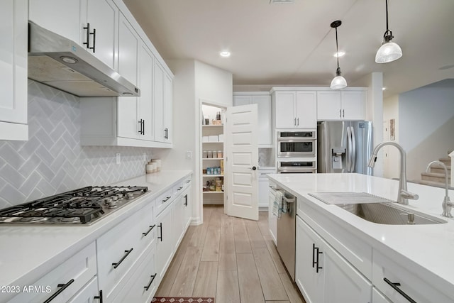 kitchen featuring white cabinetry, backsplash, appliances with stainless steel finishes, light wood-type flooring, and pendant lighting