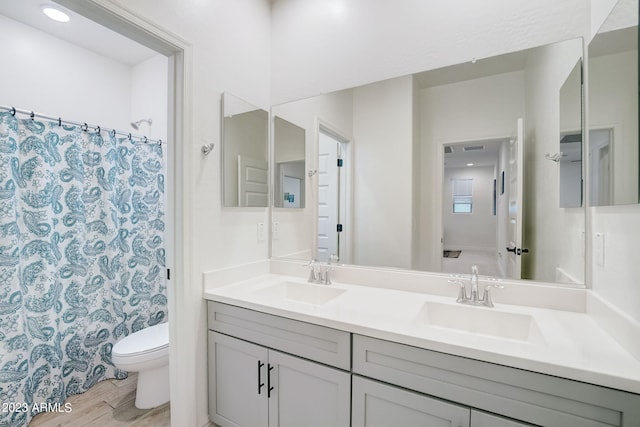 bathroom featuring toilet, large vanity, and double sink