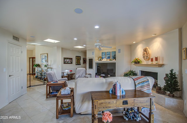 living room featuring recessed lighting, a skylight, visible vents, a ceiling fan, and a fireplace