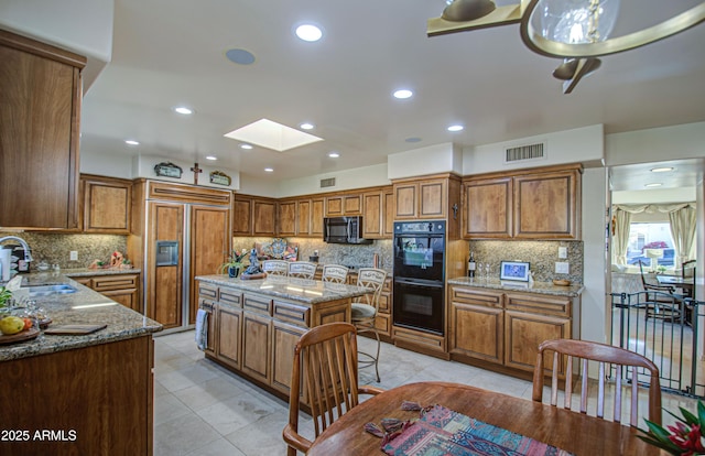 kitchen featuring a sink, visible vents, black appliances, and brown cabinetry