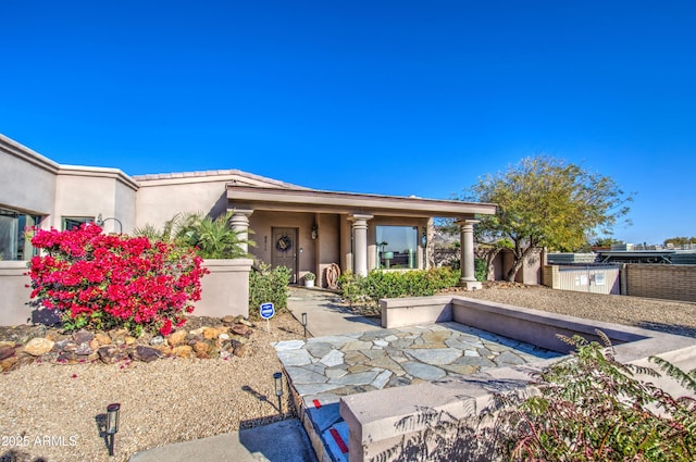 view of front of property featuring a patio area, stucco siding, and fence