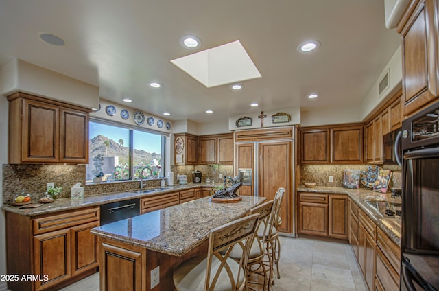 kitchen with a sink, black appliances, and brown cabinets