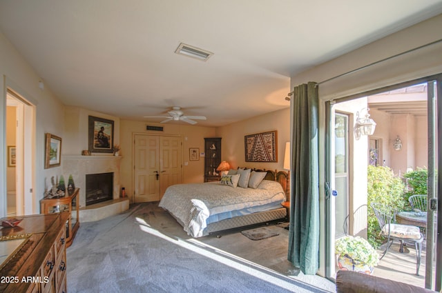 carpeted bedroom featuring ceiling fan, a closet, a fireplace, and visible vents