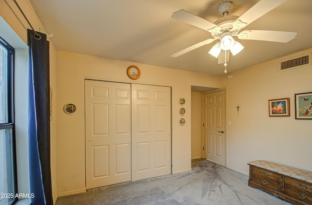 unfurnished bedroom featuring a closet, visible vents, a ceiling fan, and light carpet