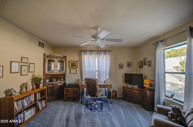 office featuring dark carpet, ceiling fan, and visible vents