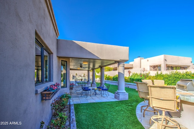 view of patio with a ceiling fan, an outdoor kitchen, and fence
