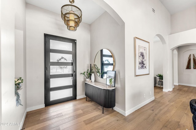 8742 E Villa Cassandra Dr, Scottsdale, AZ 85266 - entryway featuring arched walkways, a wealth of natural light, a chandelier, and hardwood / wood-style flooring