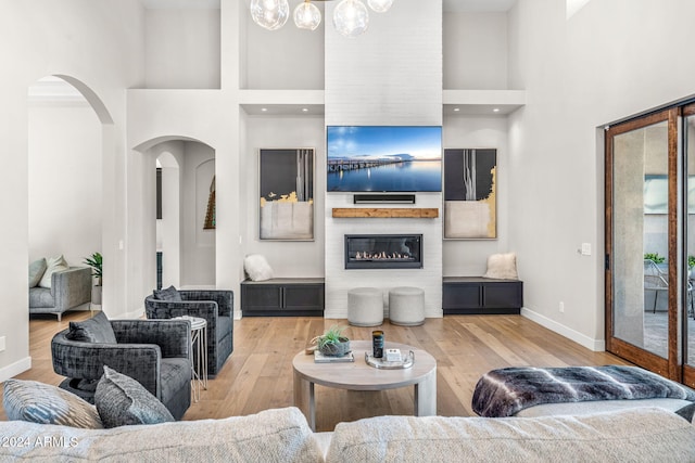 living room with a fireplace, a high ceiling, and light wood-type flooring