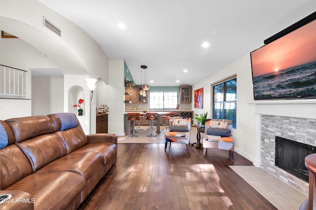 living room featuring a stone fireplace and dark hardwood / wood-style flooring