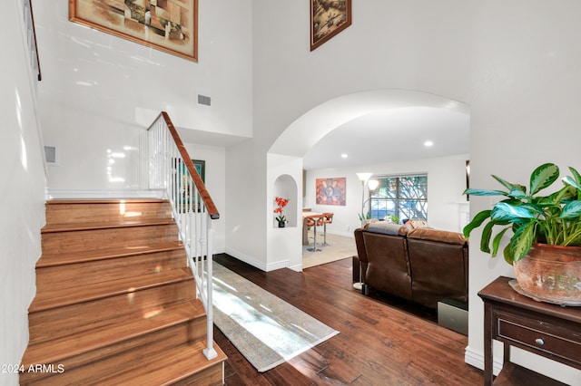 stairs with hardwood / wood-style floors and a high ceiling